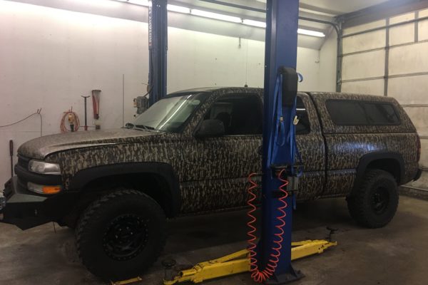 Large SUV with camoflage paint job in shop for maintenance