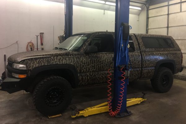 Large SUV with camoflage paint job in shop for maintenance