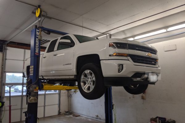 White Chevy Silverado elevated in shop for maintenance